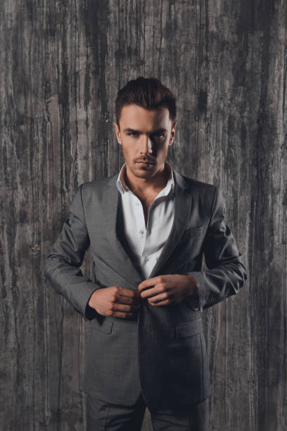 istock Handome man in suit on the grey background fastening buttons 1154978022