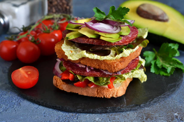 istock Crispy sandwich with salami, salad and vegetables on the kitchen table. View from above. 1154982998