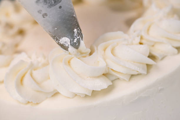 istock Decorating a white cake with cream from the pastry bag. Macro shot, closeup. 1154983342