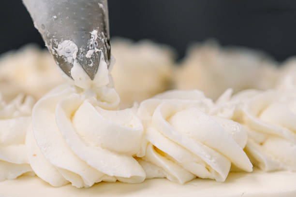 istock Decorating a white cake with cream from the pastry bag. Macro shot, closeup. 1154983363