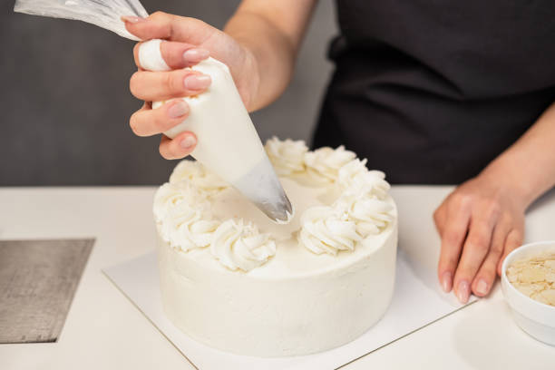 istock Confectioner at work. Cream cake decorating. Cook table preparing a cake. 1154983388