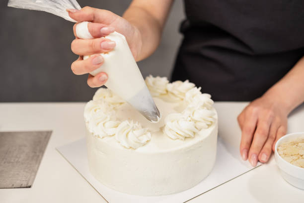 Confectioner at work. Cream cake decorating. Cook table preparing a cake. stock photo