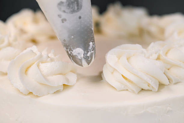 istock Decorating a white cake with cream from the pastry bag. Macro shot, closeup. 1154983402