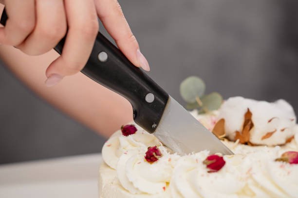 istock A condater cuts a beautiful fresh decorated white cake with a large knife. 1154983490