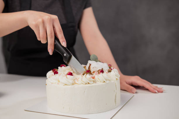 istock A condater cuts a beautiful fresh decorated white cake with a large knife. 1154983531