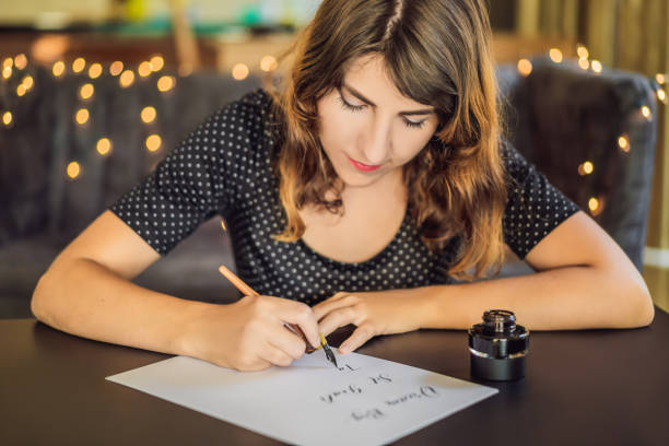 objectifs grand ensemble de rêve prendre des mesures. calligraphe young woman écrit une phrase sur le livre blanc. inscrire des lettres ornementales décorées. calligraphie, graphisme, lettrage, écriture manuscrite, concept de création - women white caucasian image created 19th century photos et images de collection