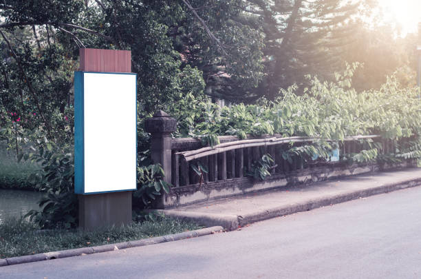 istock digital big blank billboard white LED screen vertical outstanding in the park in city side the road for display advertisement text template promotion new brand at outdoor with green tree background. 1155009564