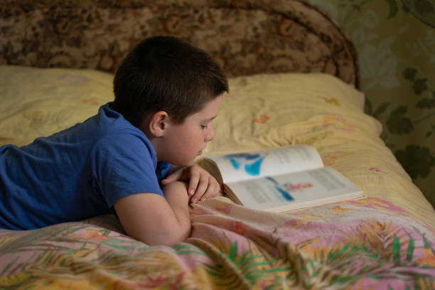 istock Boy reading a book lying on the bed 1155009887