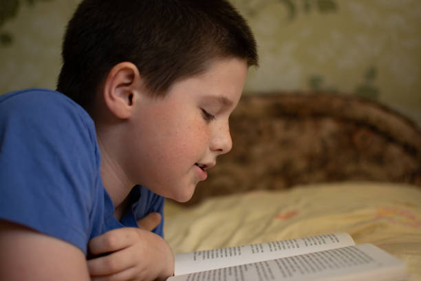 istock Boy reading a book lying on the bed 1155009938