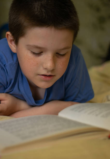 istock Boy reading a book lying on the bed 1155009993