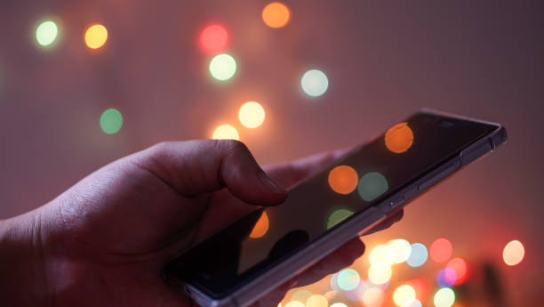 istock woman holding and using her mobile phone at night and bokeh light background 1155014294