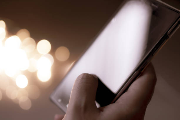 istock woman holding and using her mobile phone at night and bokeh light background 1155014303