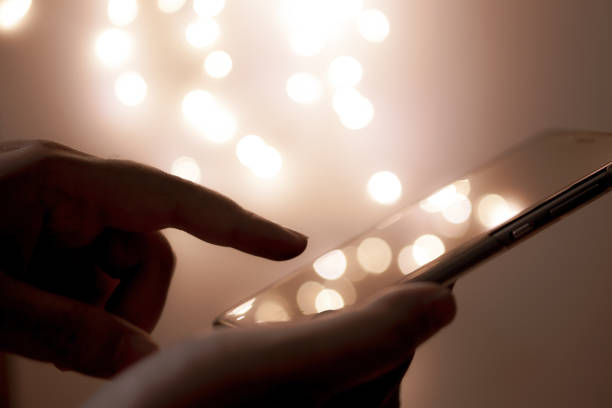 istock woman holding and using her mobile phone at night and bokeh light background 1155014314