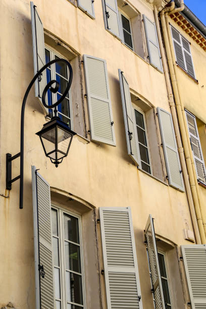 istock Traditional window shutters and iron light fixture - view from below looking unto open windows in Europe 1155014454