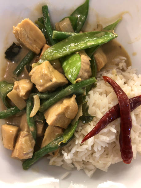 image of homecooked thai green curry recipe with boiled white rice served in white dish with onions, mange tout peas, green french beans, frozen chicken breast, coconut milk, thai chicken curry from thailand restaurant, asian non-veg vegetable stir fry - non veg imagens e fotografias de stock