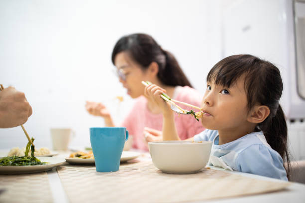 istock Girl eating lunch with spoon and chopsticks 1155015925