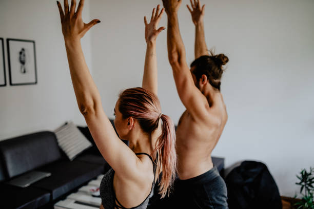 istock Young couple doing yoga together at home 1155017929