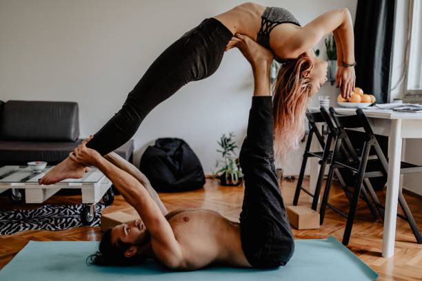 novio y novia haciendo acroyoga en casa - stretching boyfriend indoors lifestyles fotografías e imágenes de stock