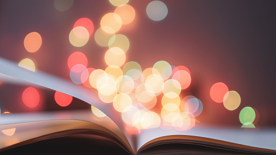 flipping and opening the book page on colorful light blurred bokeh for education, reading, knowledge, fiction, fairy concept background