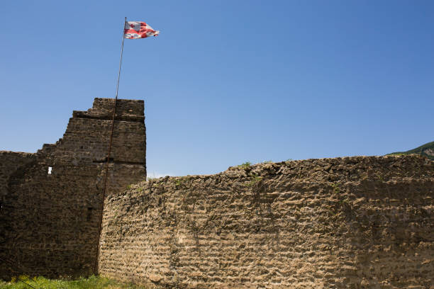 Flag of Georgia developing on ruined fortress in Mtskheta city on sunny day with blue sky, Georgia.