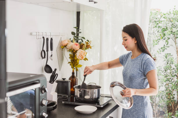 jeune femme asiatique faisant la nourriture saine dans la cuisine à la maison - making soup photos et images de collection