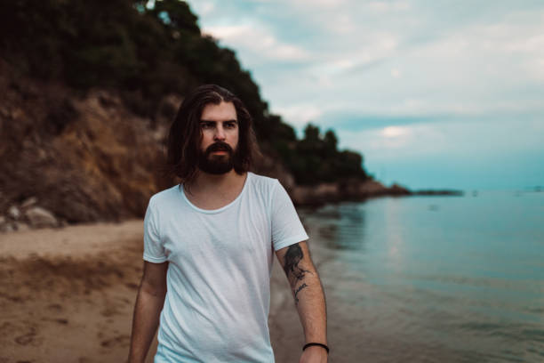 Portrait of a handsome bearded man walking at the beach and enjoying sunny day