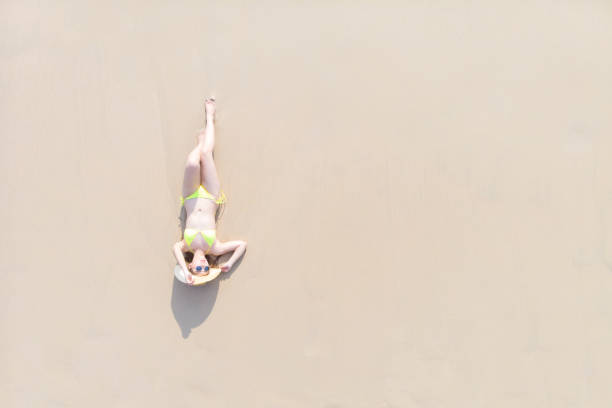 istock Young woman laying on sand beach 1155036797