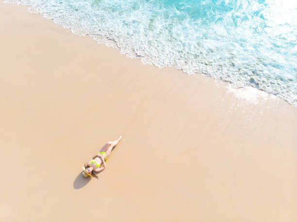 istock Young woman laying on sand beach 1155036841