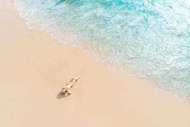 istock Young woman laying on sand beach 1155036929