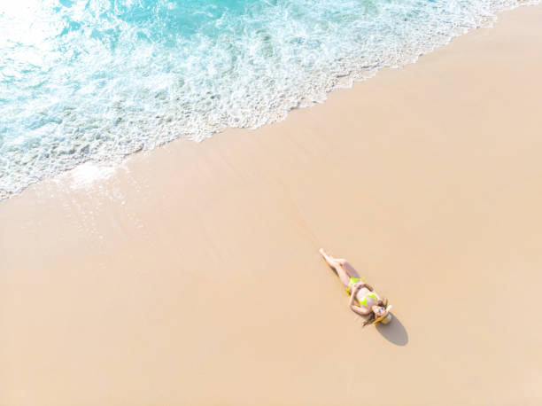 istock Young woman laying on sand beach 1155036931