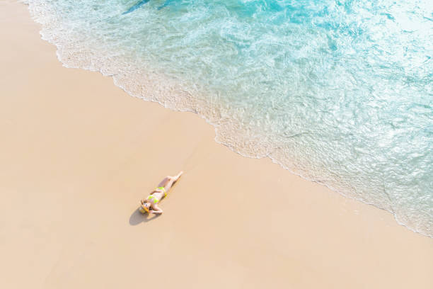 istock Young woman laying on sand beach 1155036941