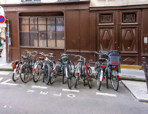Bunch of different bicycles of local Parisians stand along the old building on the street ready to take cyclists for bike trip to any point of old historic Paris with narrow streets and heavy traffic