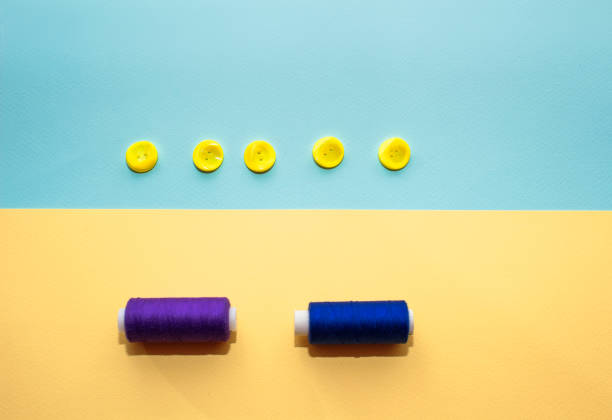 istock Composition with dark blue threads and sewing accessories on yellow background. Yellow buttons on blue background. Flatlay, place for text 1155039818