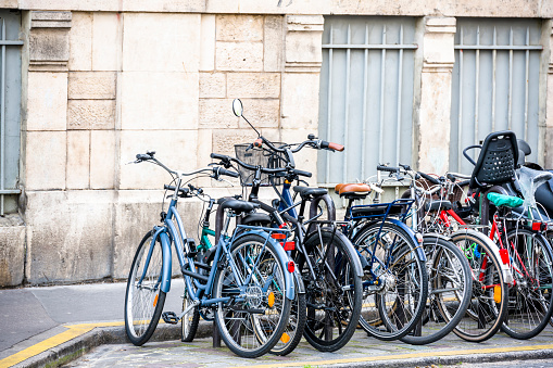 Bunch of different bicycles of local Parisians stand along the old building on the street ready to take cyclists for bike trip to any point of old historic Paris with narrow streets and heavy traffic