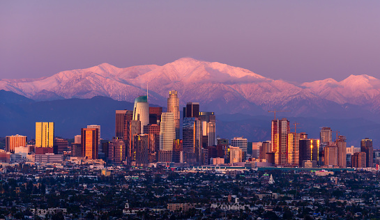 El horizonte del centro de los Ángeles con montañas cubiertas de nieve detrás del crepúsculo photo