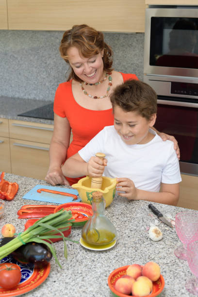 счастливые мать и сын готовят обед с минометом - family with one child domestic life caucasian love стоковые фото и изображения