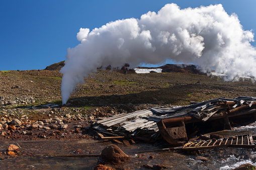 Emission of mineral natural thermal water, steam (steam-water mixture) from geological well in geothermal deposit area, geothermal power station, slope of active Mutnovsky Volcano, Kamchatka Peninsula