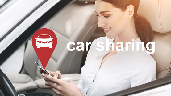 Sharing economy. Business woman using car sharing mobile application, sitting in rental transportation, panorama