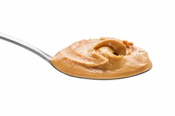 Peanut spread in spoon isolated on white background