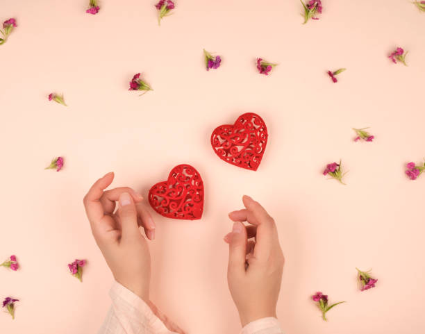 istock two female hands and  red hearts 1155046180