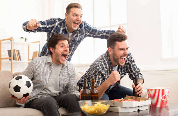 Excited friends watching football match and shouting Excited friends watching football match and shouting, cheering for favourite team at home leasure games stock pictures, royalty-free photos & images