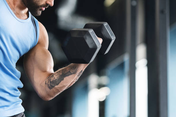 istock Muscular athlete making strength exercise for biceps with dumbbell 1155046398
