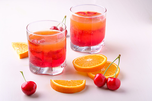 Jelly dessert with strawberries in drink glass with cherry berries and orange slices nearby