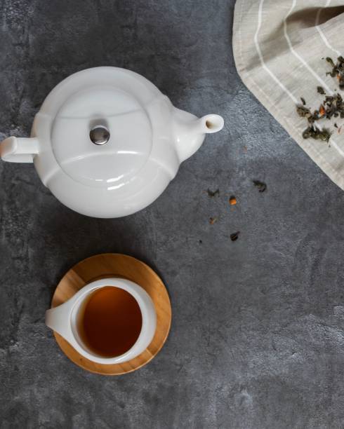Teapot, Cup of tea and textiles on grey background
