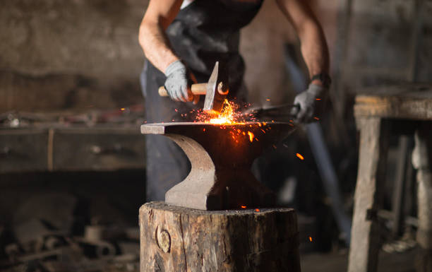 el herrero forja manualmente el metal fundido - herramientas de herrero fotografías e imágenes de stock