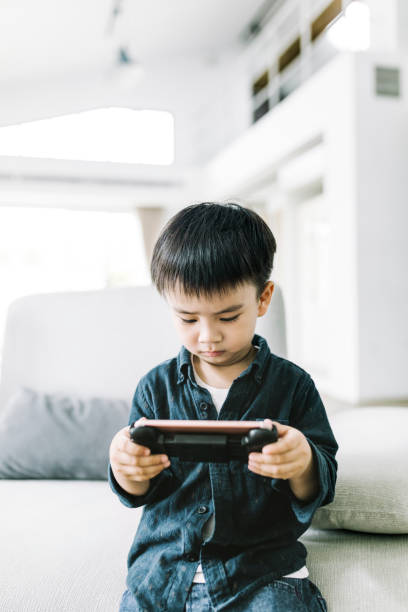 istock Cute boy playing game on smart phone at home 1155050714