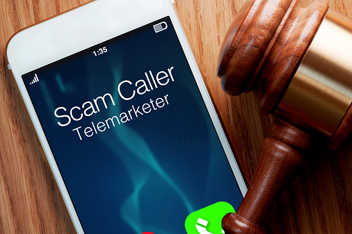 Telemarketer robocaller scam calling smartphone with woman holding telephone in house