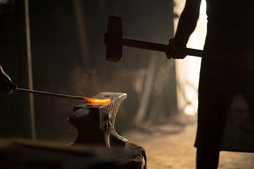 Blacksmith manually forging the molten metal