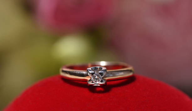istock Beautiful engagement ring with a diamond on a red surface. Closeup macro for template for text. 1155052479