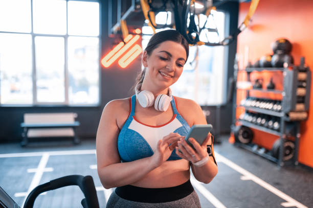 istock Young woman reading messages on phone before workout 1155059179